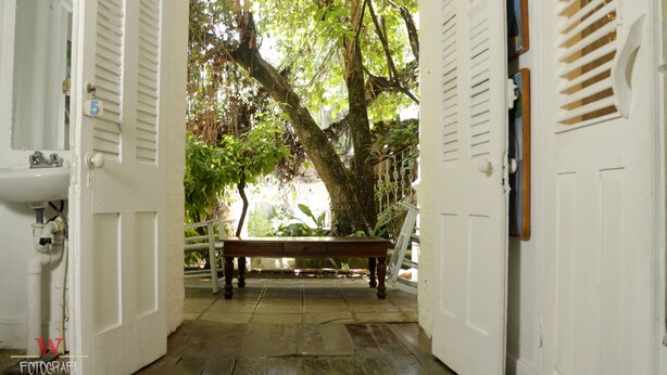 An open doorway leading to a covered outdoor area with a bench and a tree.