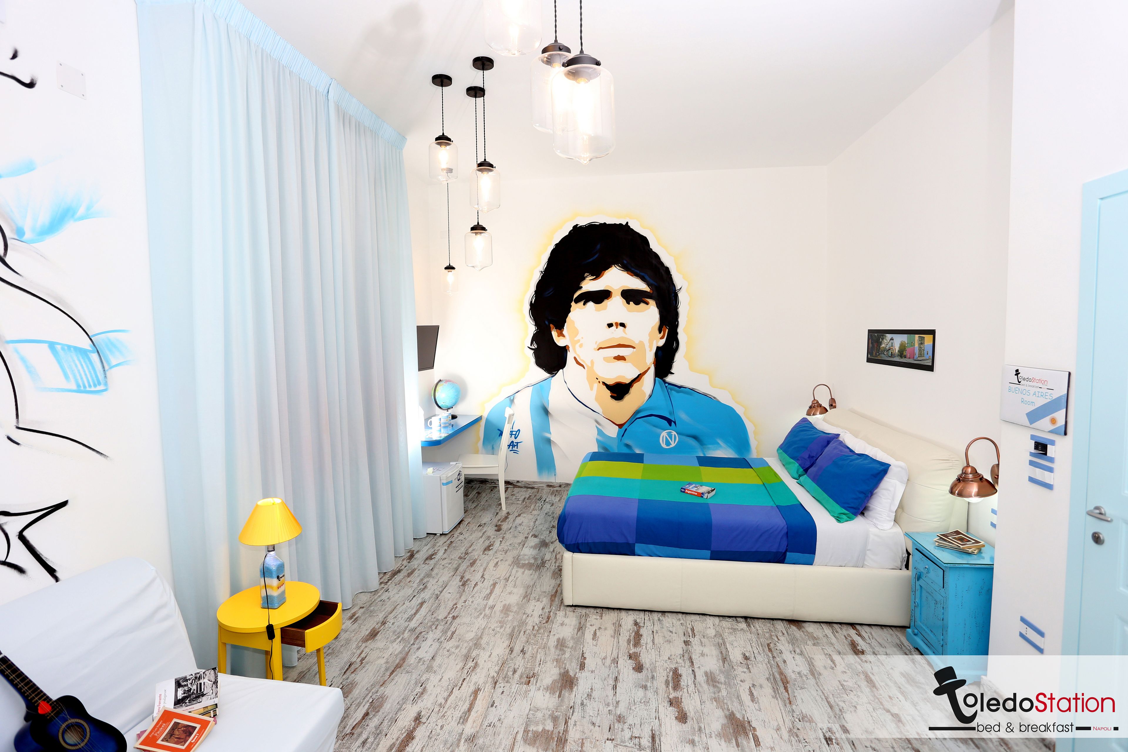 Una camera da letto con un letto, un comodino, una lampada e una chitarra.
