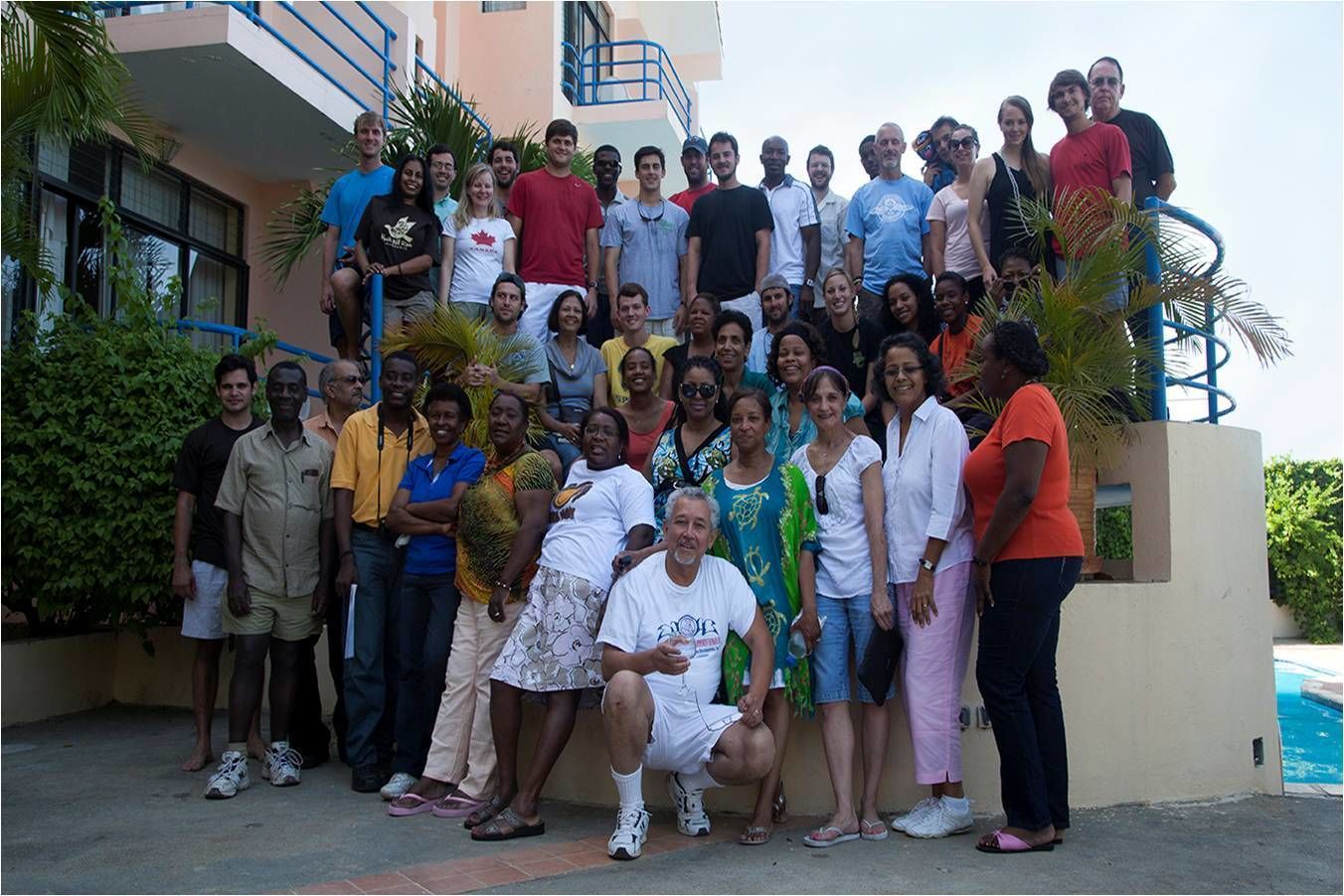 A group of people posing on a balcony with a pool in the background.