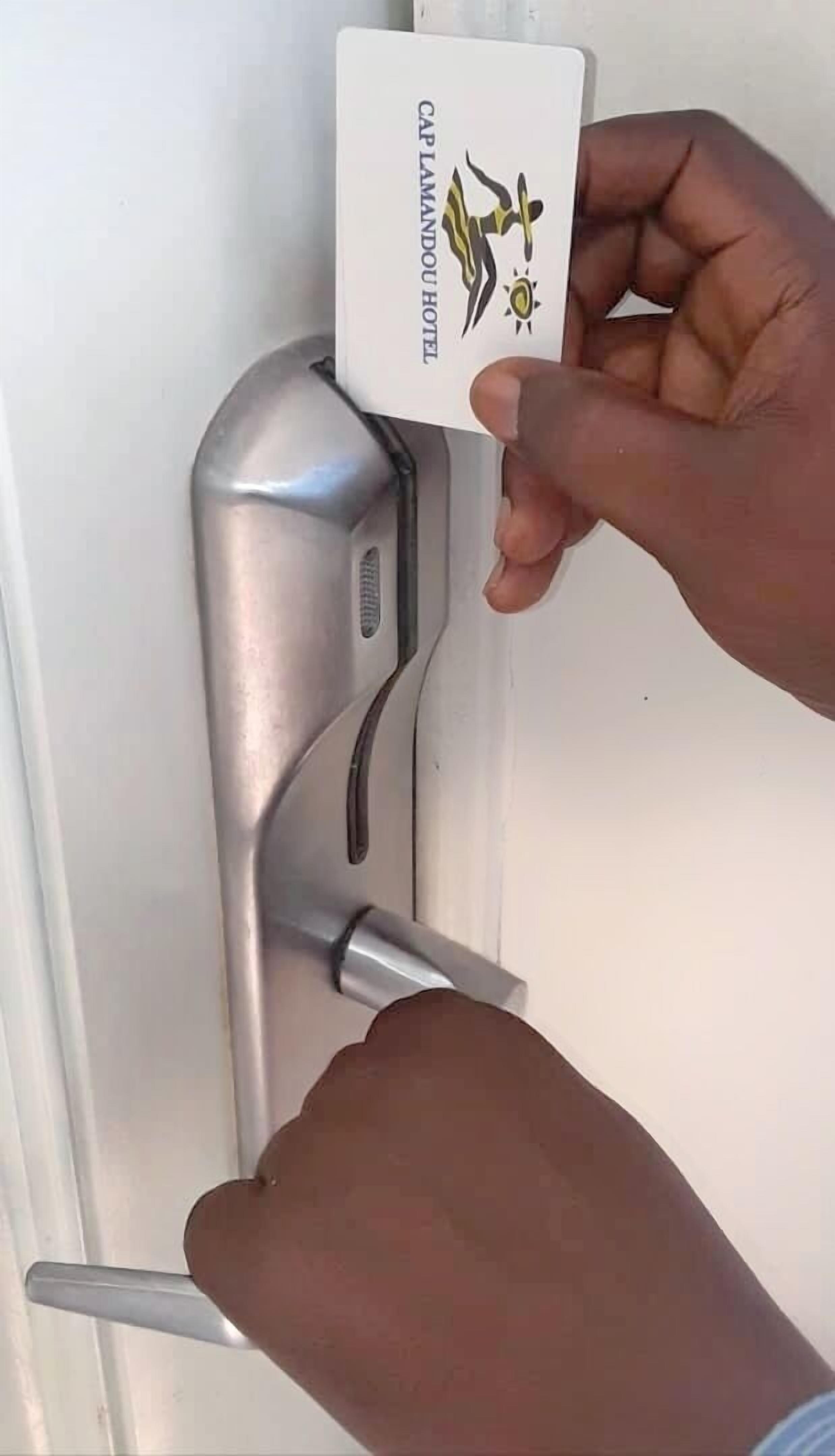 Une main insérant une carte dans le mécanisme de verrouillage d’une porte.