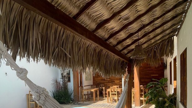 A pool area with a hammock, wooden furniture, and a thatched roof structure. - Villa Chic Pousada (Jijoca de Jericoacoara)