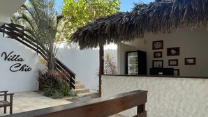 A villa with a thatched roof, a staircase, and a reception desk with framed pictures. - Villa Chic Pousada (Jijoca de Jericoacoara)