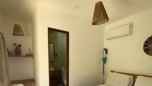 A bedroom with a bed, a bedside table, a hanging lamp, a shelf with decorative items, and a door leading to another room. - Villa Chic Pousada (Jijoca de Jericoacoara)