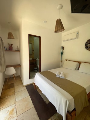 Ein Schlafzimmer mit Bett, Nachttisch, einer Hängelampe, einem Regal mit Dekoration und einer Tür zu einem anderen Raum.