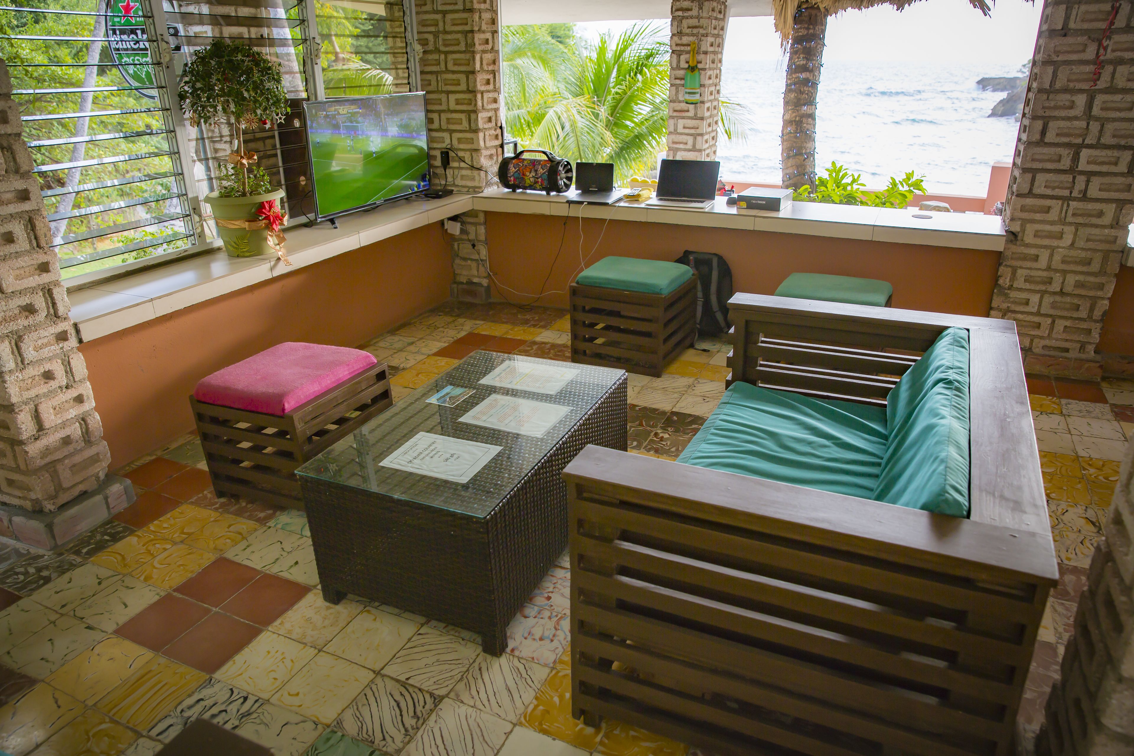 A room with a beach view, a TV, a laptop, and a sofa.