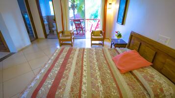 Habitació d'hotel amb un llit gran, dues cadires, una taula petita i vista a un balcó amb cadires.