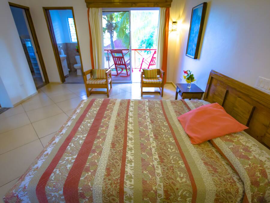Habitació d'hotel amb un llit gran, dues cadires, una taula petita i vista a un balcó amb cadires.