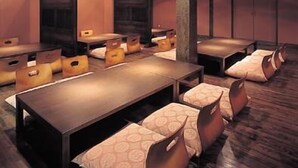 Une pièce dotée de plusieurs espaces de détente, comprenant des tables et des bancs rembourrés, disposés dans un aménagement spacieux.