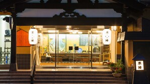 Un restaurant japonais traditionnel avec une entrée constituée d’une porte coulissante en verre, un escalier menant à l’étage et une enseigne ornée de caractères japonais.