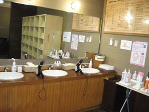 A hotel bathroom with two sinks, a mirror, and various toiletries. - Oyado Honjin (Yuzawa)