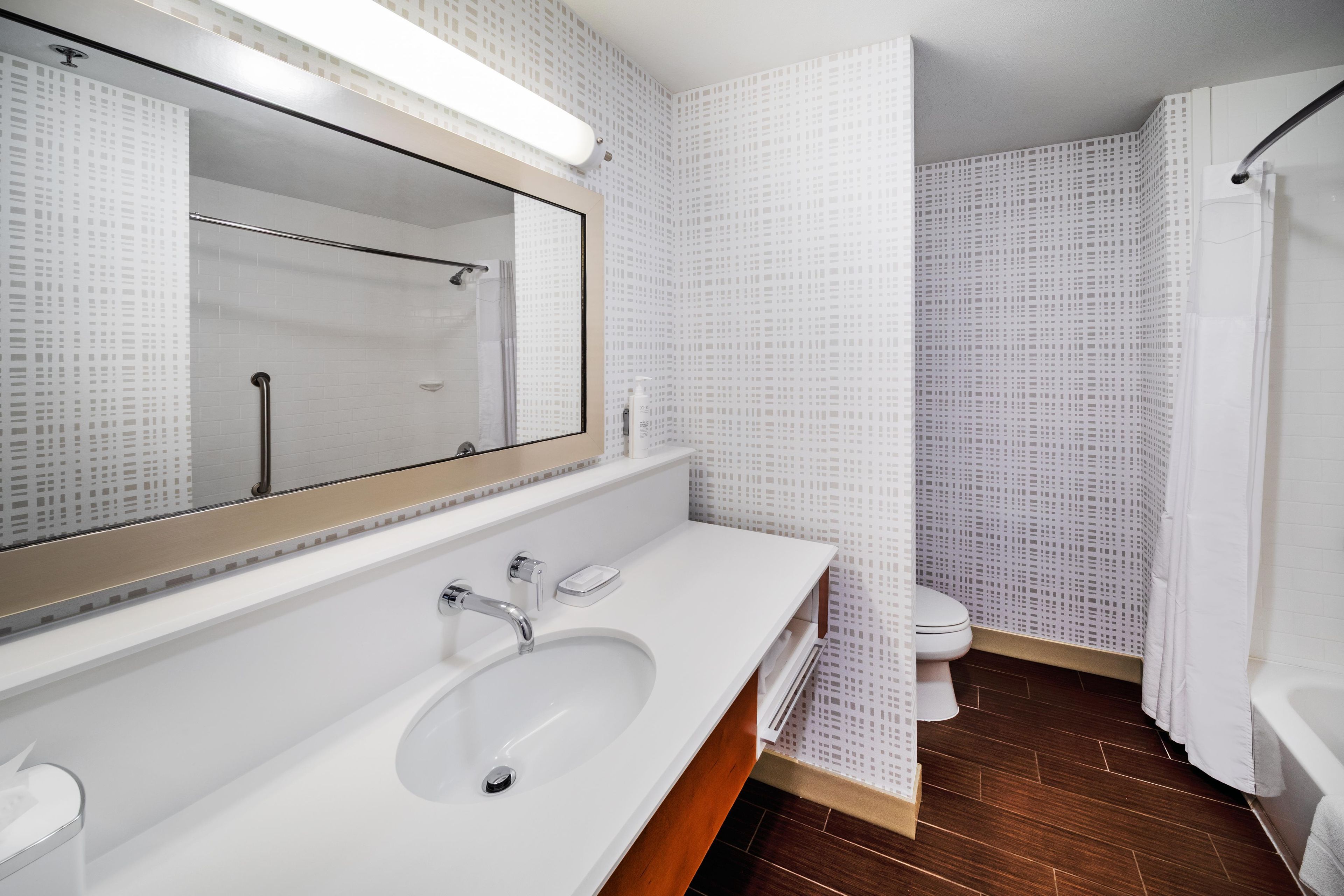 Une salle de bain moderne avec un grand miroir, un lavabo, une douche et des toilettes.