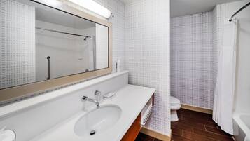 Une salle de bain moderne avec un grand miroir, un lavabo, une douche et des toilettes.