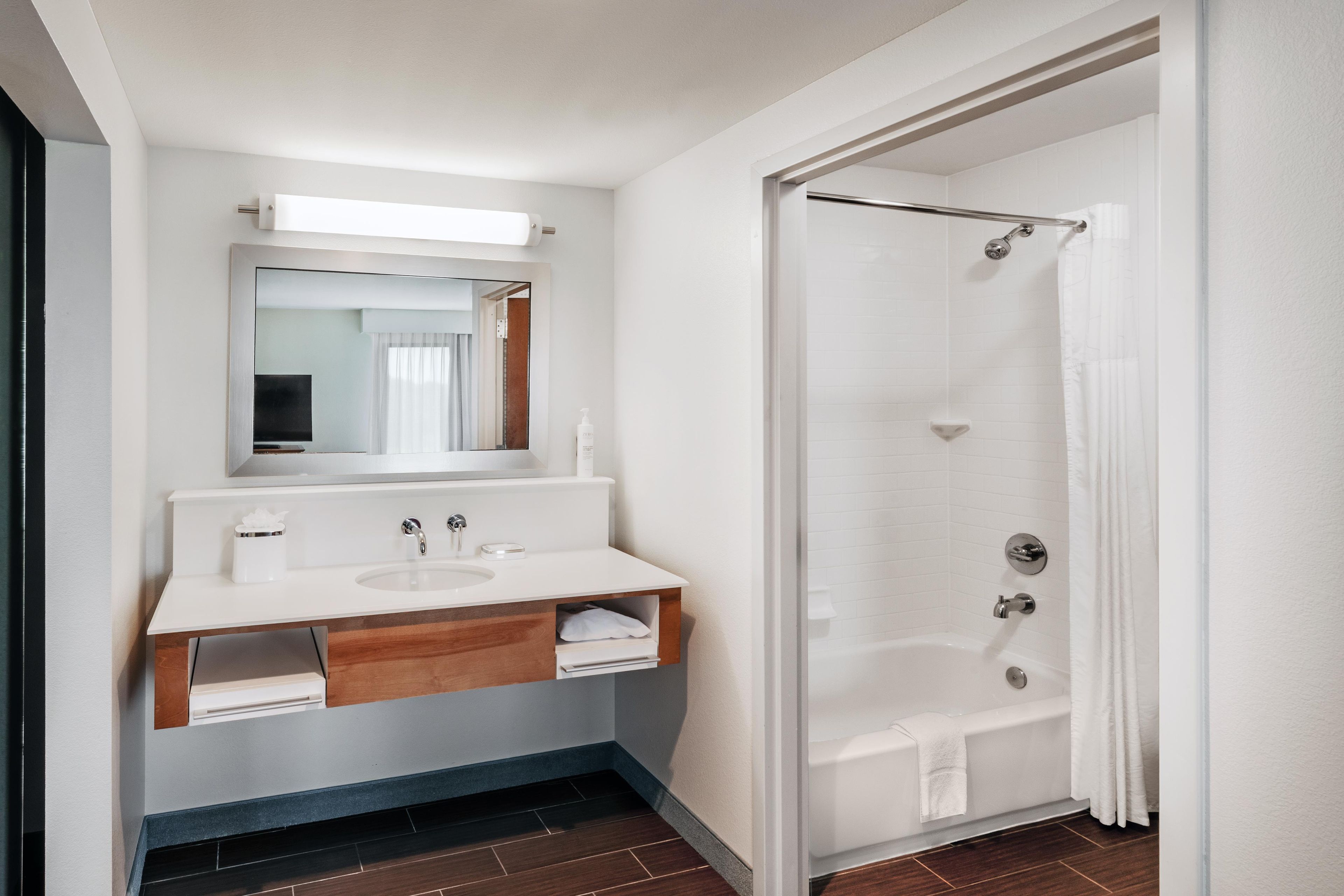 A modern bathroom with a white sink, mirror, and shower.