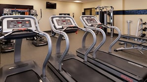 A gym with treadmills, weight machines, and a wall-mounted TV. - Hampton Inn & Suites by Hilton Lonoke (Lonoke)