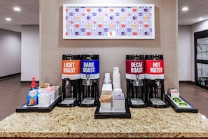 A coffee station with four coffee dispensers labeled 'Light Roast,' 'Dark Roast,' 'Decaf Roast,' and 'Hot Water.' There are also coffee pods and a bottle of creamer. - Hampton Inn & Suites by Hilton Lonoke (Lonoke)