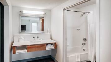 Un baño moderno con lavamanos, espejo y ducha blancos.