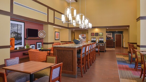 A hotel lobby with a central island, seating arrangements, and a kitchen area. - Hampton Inn & Suites by Hilton Lonoke (Lonoke)