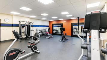 A gym with various exercise equipment including treadmills, weight machines, and dumbbells.