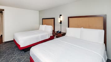Une chambre d’hôtel avec deux lits simples, une table de chevet avec un téléphone et une lampe fixée au mur.