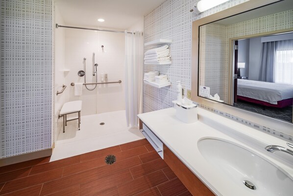 A modern bathroom with a walk-in shower, a large mirror, a vanity with a sink, and a toilet.