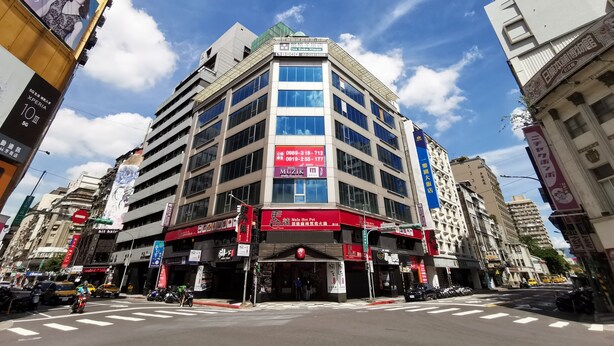 A multi-story hotel with a prominent red sign for 'MUZIK' on the ground floor, large windows, and a modern architectural design. - Inn Cube Ximen (Taipei)