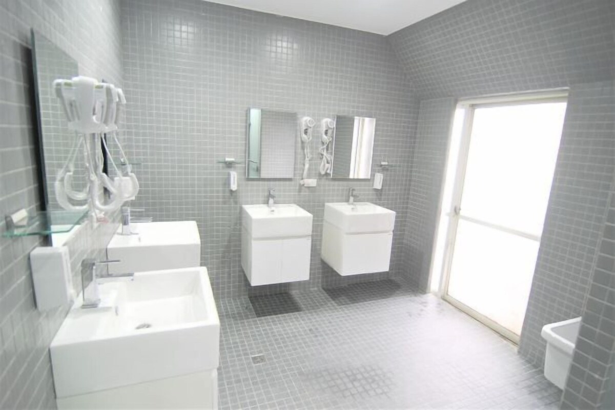 A bathroom with three sinks, a glass shower enclosure, and a large window.