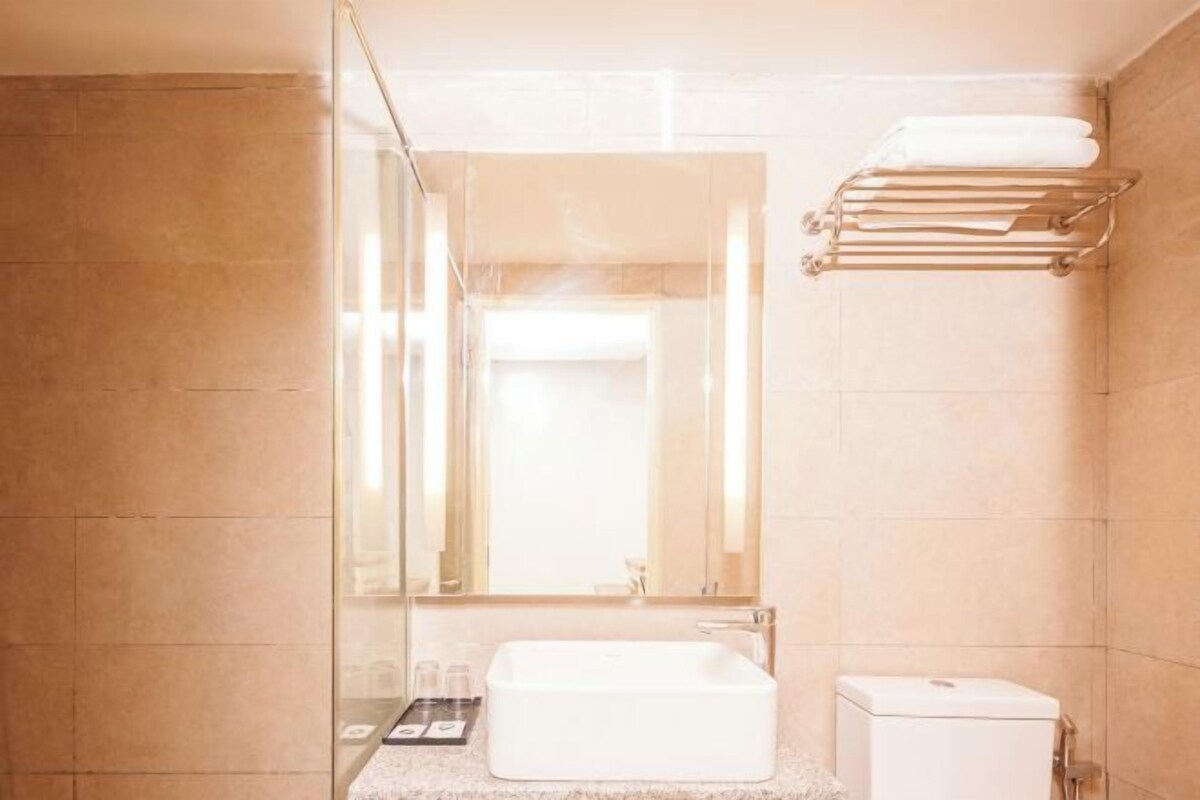 A modern bathroom with a rectangular sink, a glass shower enclosure, and a towel rack.