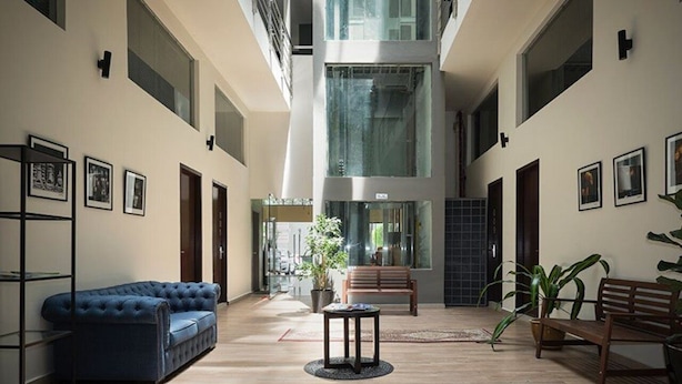 A spacious atrium with a high ceiling, a blue sofa, a wooden bench, and a small table. - The Mesui Hotel (Kuala Lumpur)