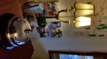 A room with a desk lamp, a clock, and a wall with various papers and photos.