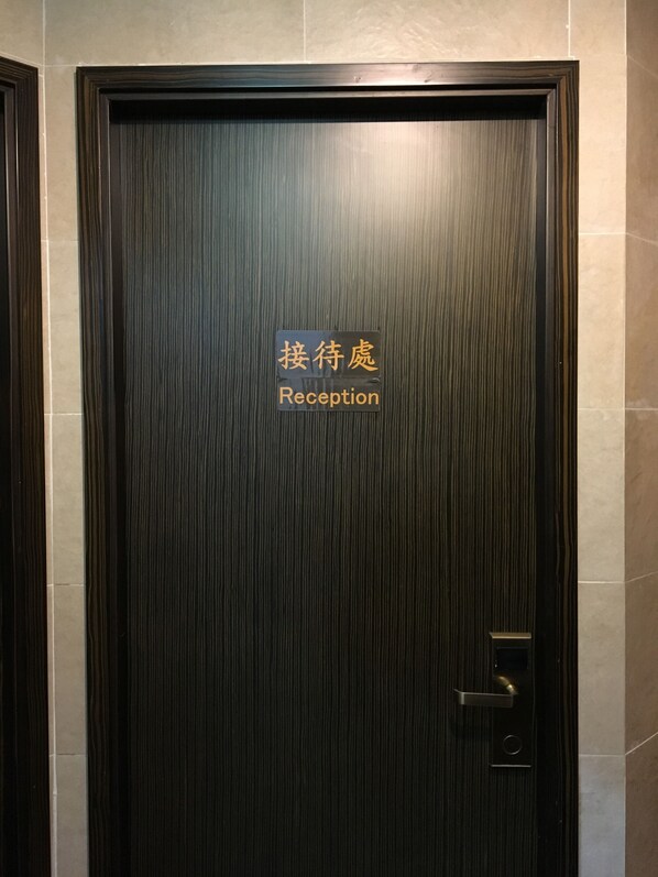 Una puerta de madera oscura con un letrero que dice 'Reception' en chino e inglés.