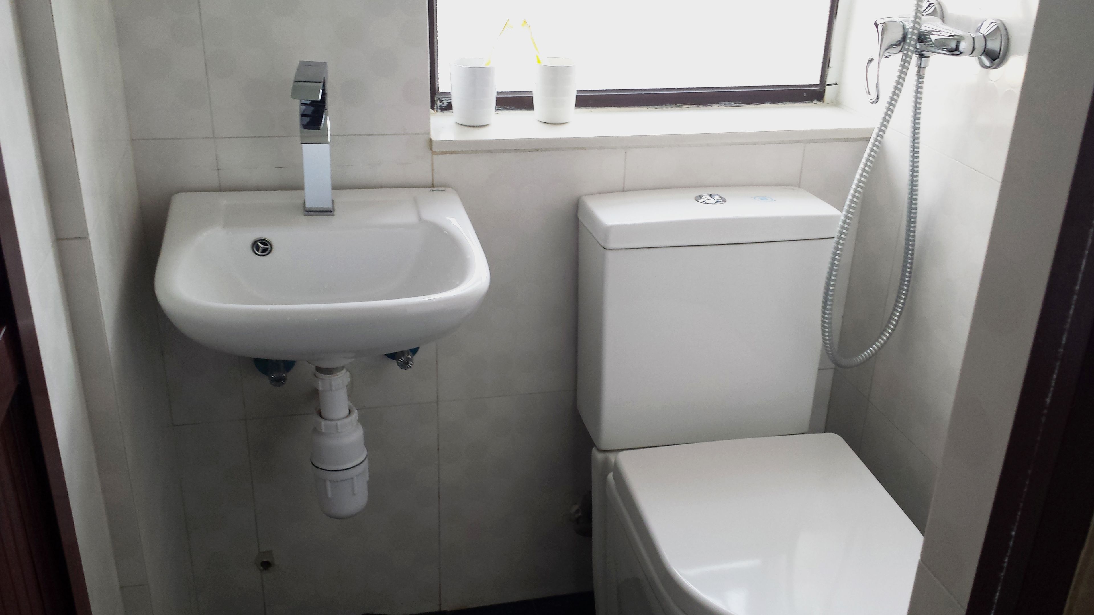 Un bagno piccolo con lavandino, WC e doccia bianchi.