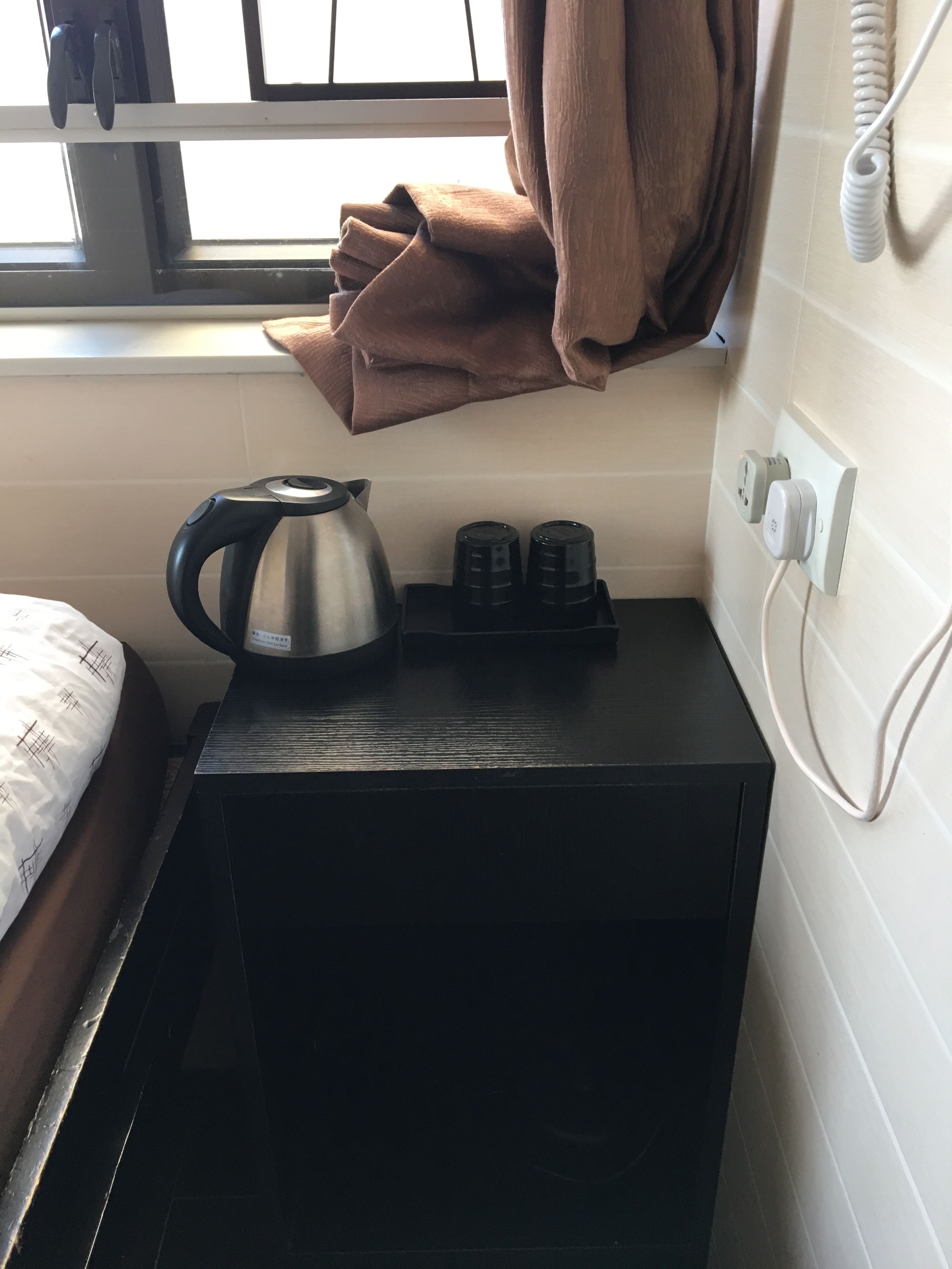 A small kitchenette with a kettle, two black electric kettles, and a power outlet.