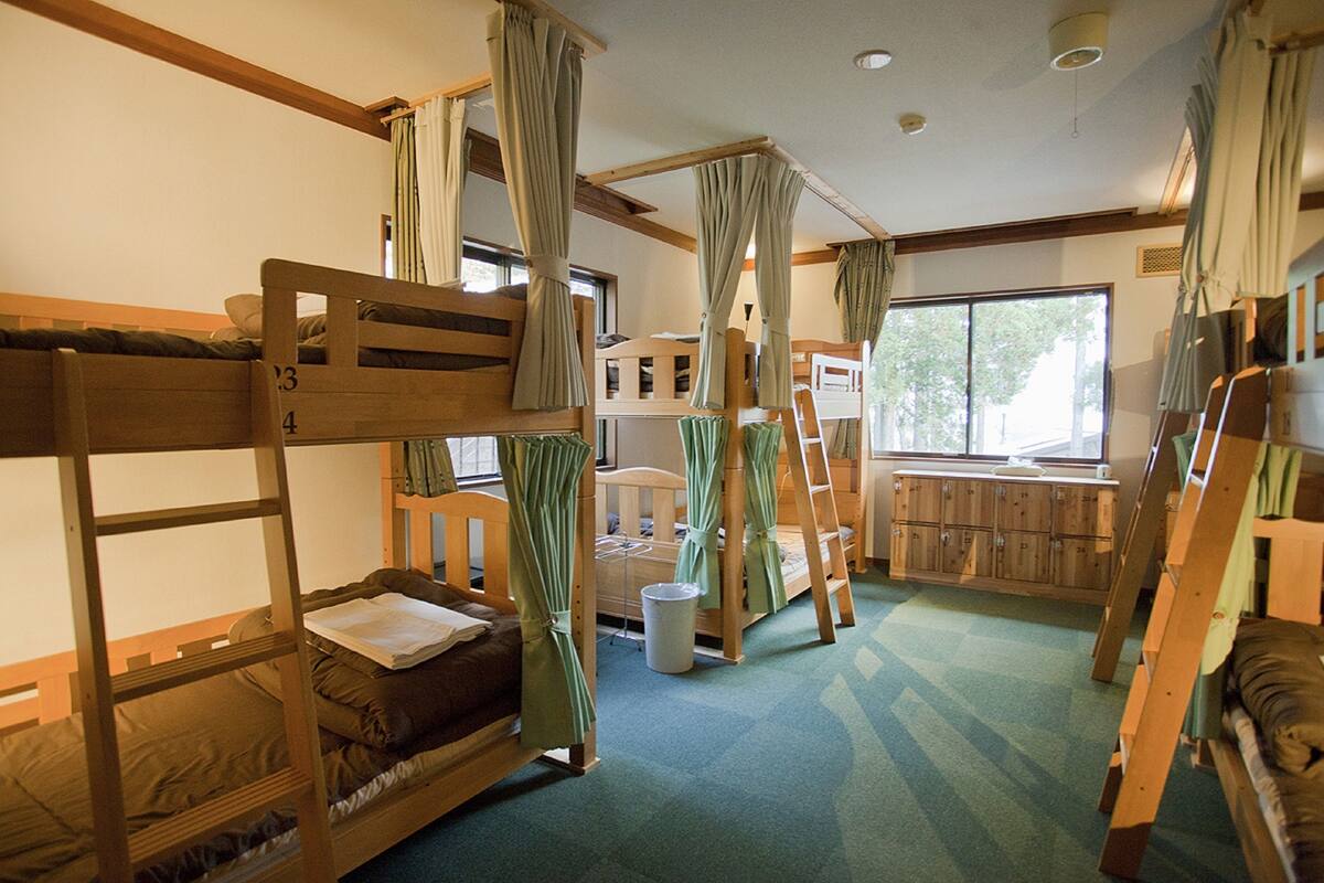 A room with bunk beds, a small desk, and a window.