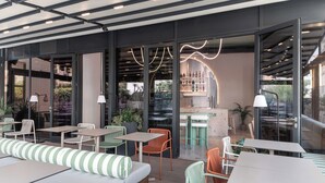 An outdoor seating area with tables and chairs, a bar, and a view of the surrounding greenery. - The View Luxury Rooms (Split)