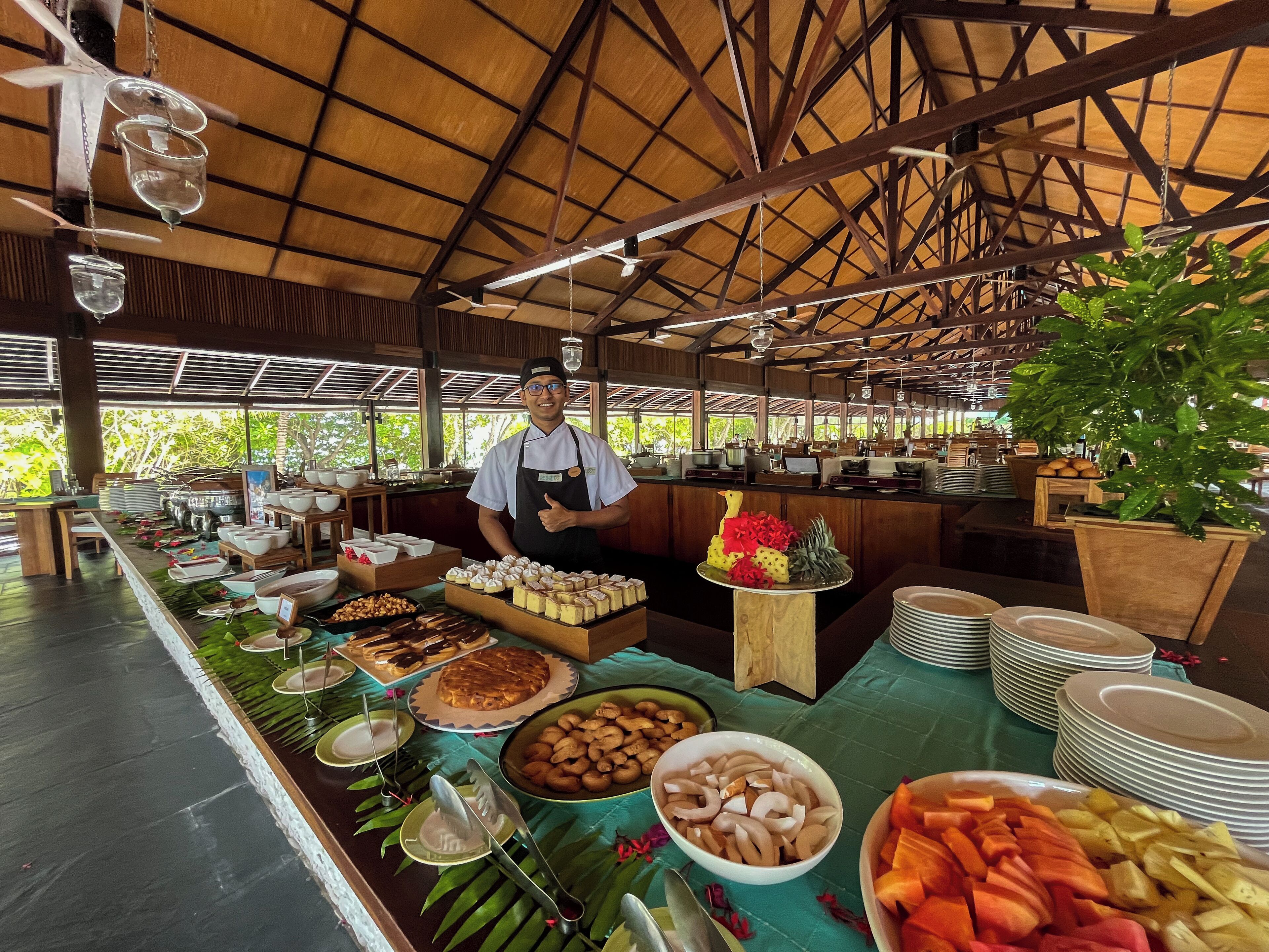 A buffet setup with various food items and a chef giving a thumbs up.