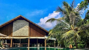 A resort with a clear pool, wooden building, and palm trees. - The Barefoot Eco Hotel (Hanimaadhoo)