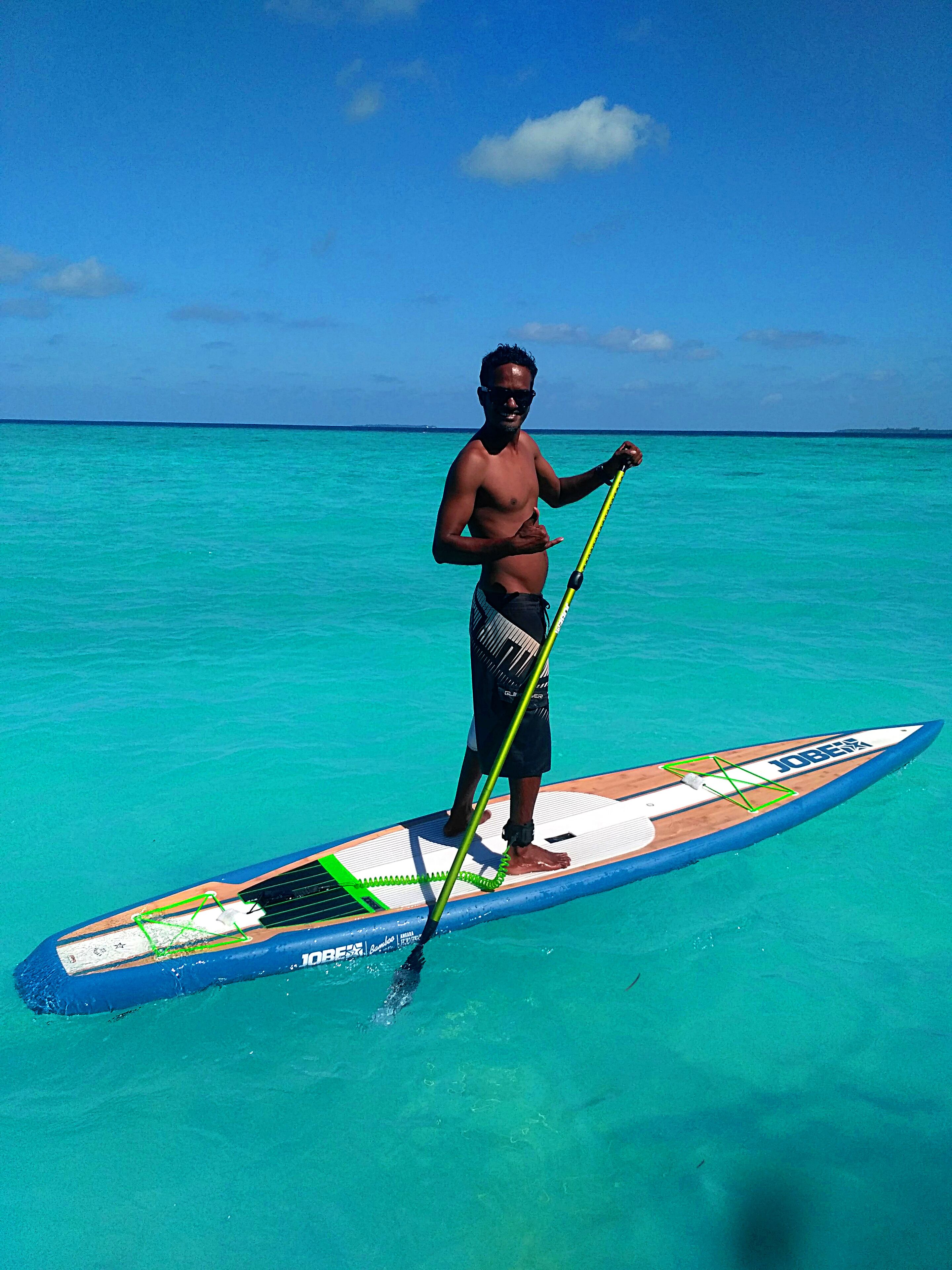 A person standing on a paddleboard in turquoise water.