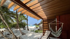 A beachside room with a hammock, wooden ceiling, and a view of the beach and palm trees. - The Barefoot Eco Hotel (Hanimaadhoo)