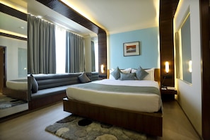 A modern bedroom with a large bed, built-in seating, and a large window with curtains.