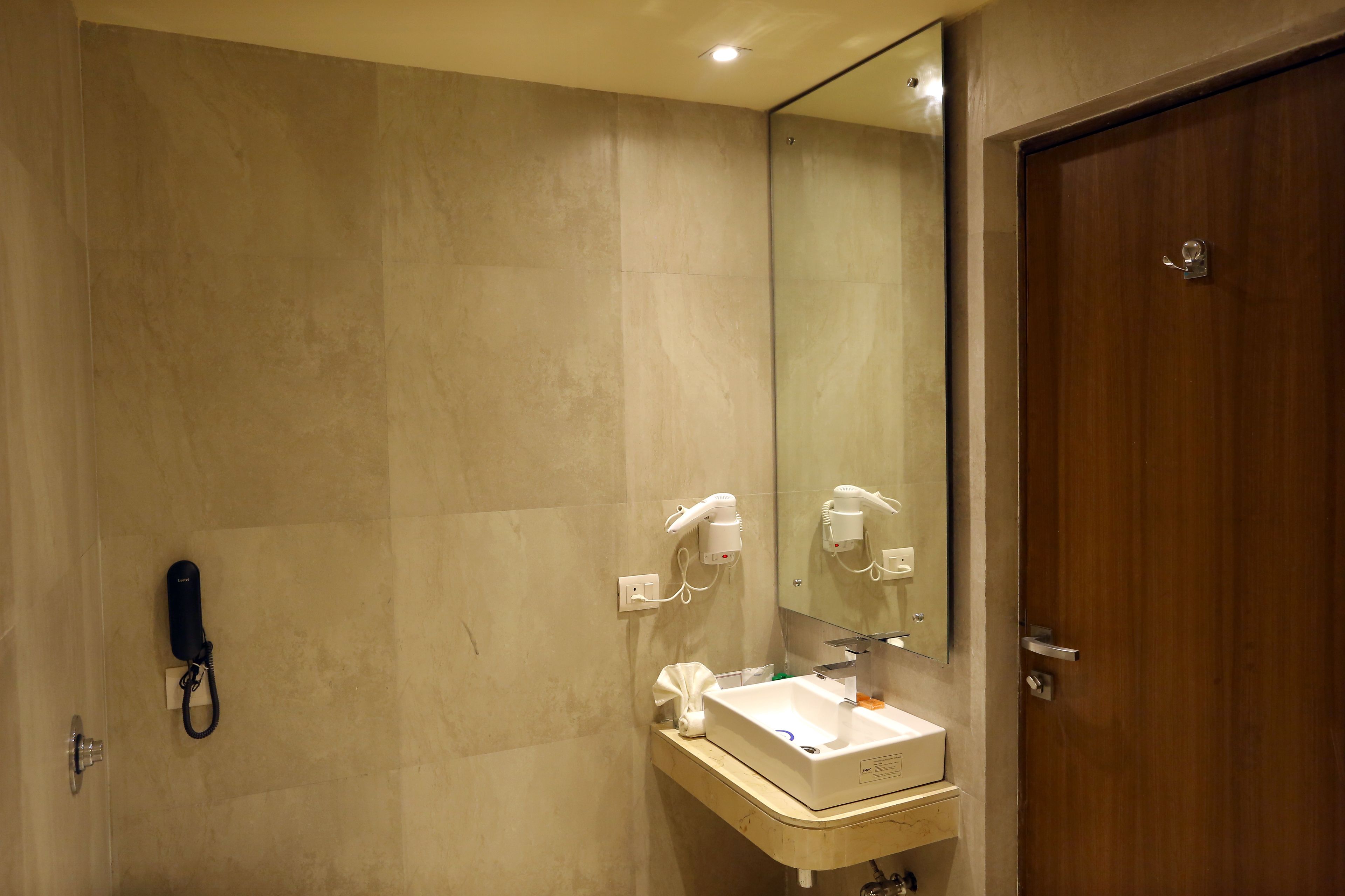 A bathroom with a shower, a sink with a mirror, and a hairdryer mounted on the wall.