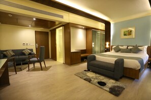 Ein modernes Hotelzimmer mit Bett, einer Couch, einem Schreibtisch und einem Spiegel.