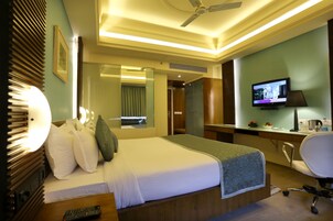 A hotel room with a bed, a desk, a chair, a television, and a bathroom.