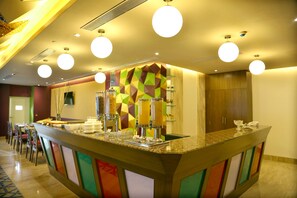 Ein Hotel-Rezeptionsbereich mit einer farbenfrohen Theke, mehreren Saftspendern und einem Telefon.