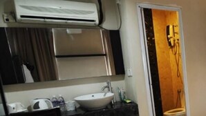 A bathroom with a sink, mirror, and shower.