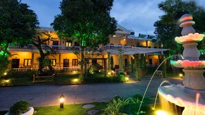 A well-lit courtyard with a fountain, trees, and a building with multiple balconies. - Kim Hoa Resort (Phu Quoc)