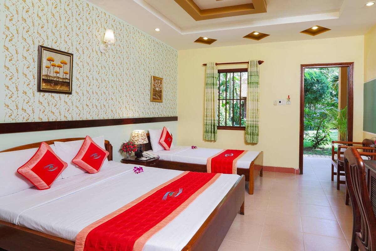 A hotel room with two beds, a desk, and a view of the outdoors.