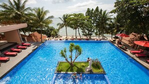 A pool with a central island, red lounge chairs, and palm trees. - Kim Hoa Resort (Phu Quoc)