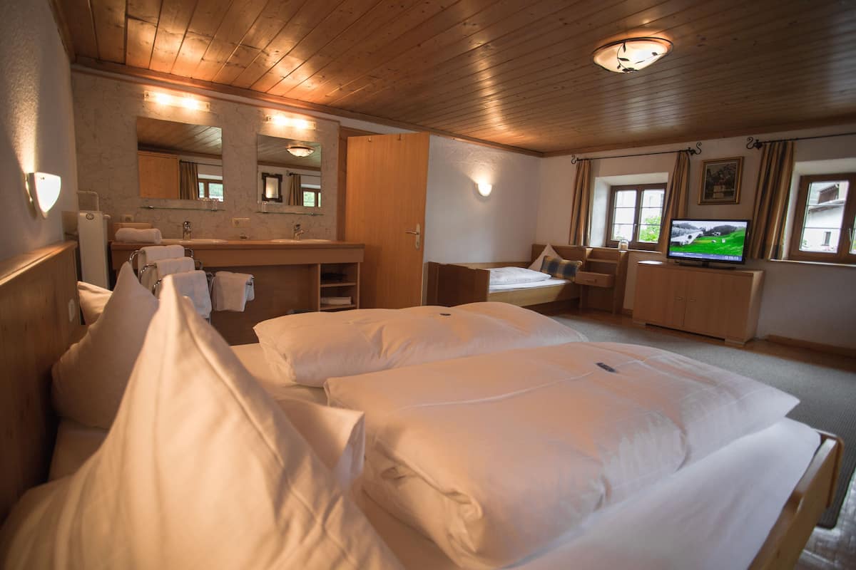Habitación de hotel con dos camas, baño con espejo, televisión y ventana con cortinas.