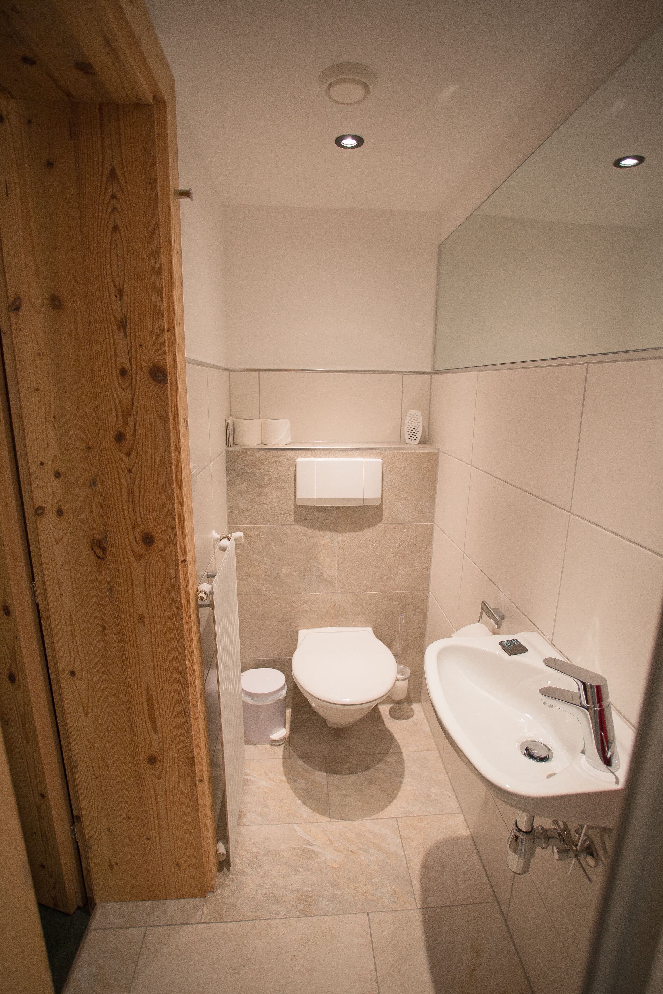 A bathroom with a toilet, sink, and wooden door.