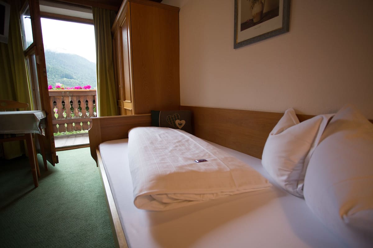 Una habitación de hotel con cama, escritorio y vista a montañas desde una ventana.